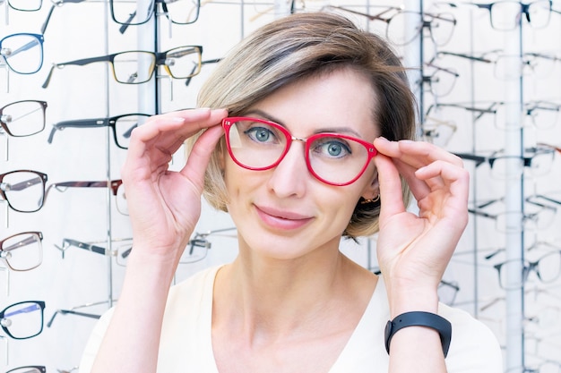 Young woman in optic store choosing new glasses with optician. glasses in the store of optics. A woman chooses glasses. Emotions. Ophthalmology.