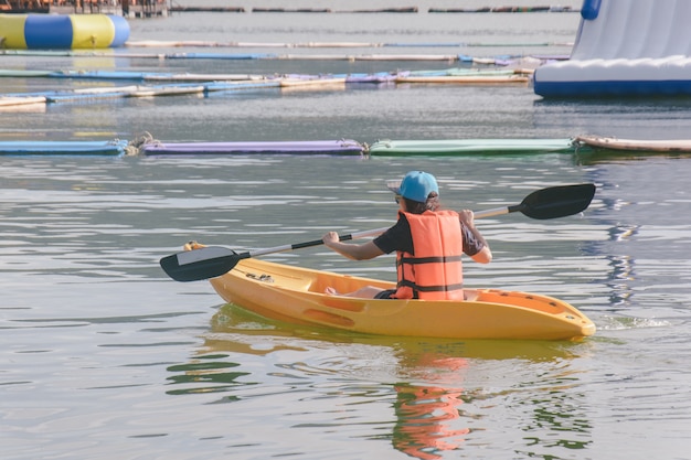 young woman in orange life jackets kayaking on a lake