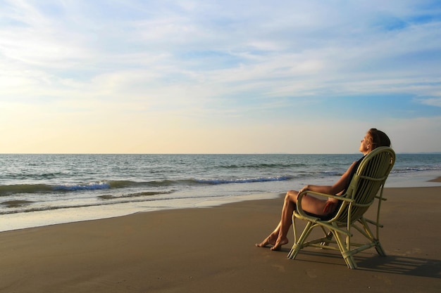 Young woman in orange swimwear sitting on the wicker chair