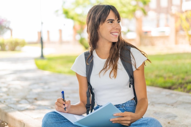 屋外でノートを持っている若い女性