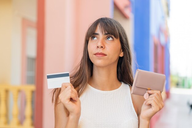 Foto giovane donna all'aperto che tiene portafoglio e carta di credito