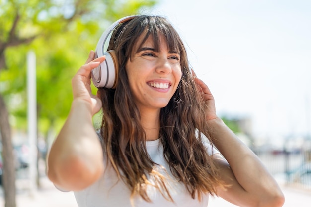 Young woman at outdoors listening music and singing