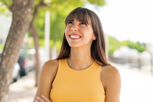 Young woman at outdoors looking up while smiling