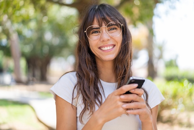 Young woman at outdoors sending a message with the mobile