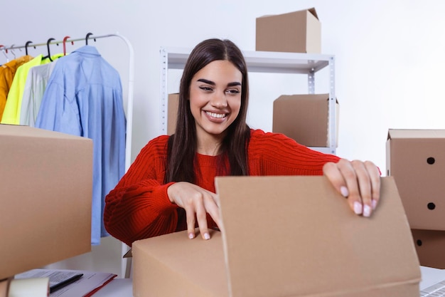 Young woman owener of small business packing product in boxes\
preparing it for delivery women packing package with her products\
that she selling online