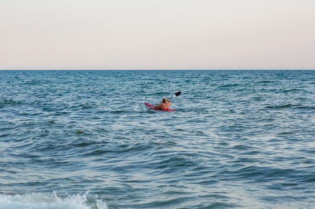 Young woman paddling the sea kayak. Active vacation.