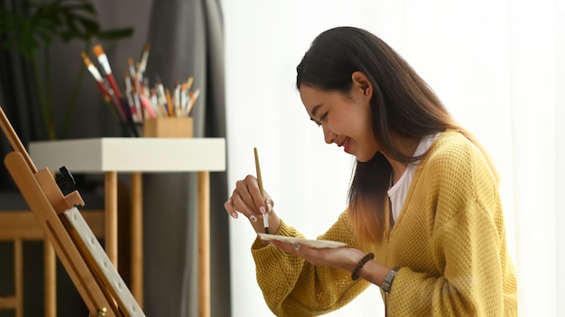 Young woman painting on a canvas at home