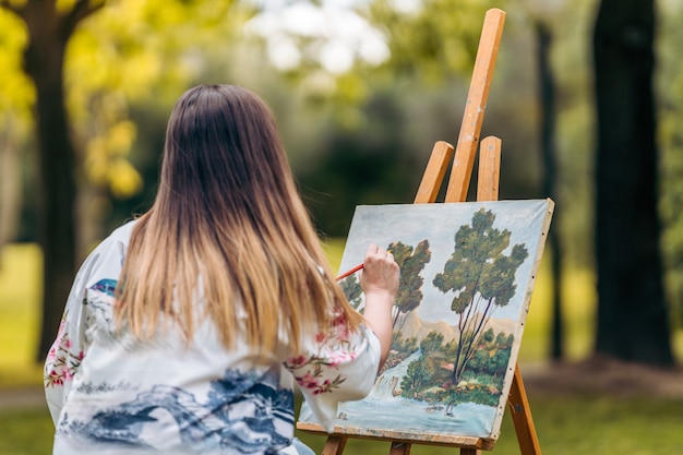 Young woman painting on a canvas in the middle of a park.