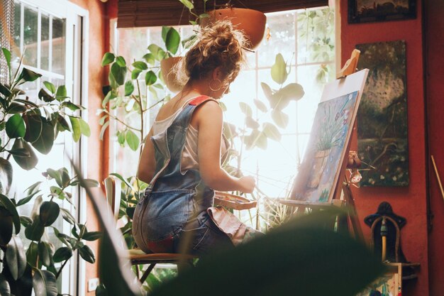 Photo young woman painting on easel