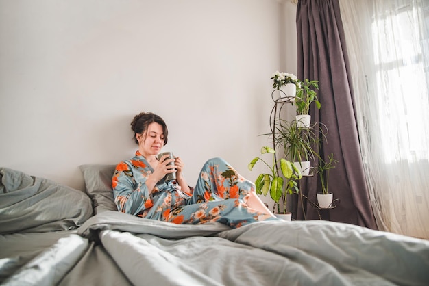 Young woman in pajama drinking tea in the morning in bed