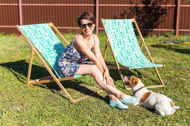 Young woman in pajama is resting in chair on a green lawn on sunny summer day village and country life