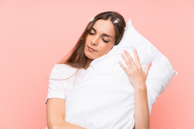 Young woman in pajamas over isolated pink wall