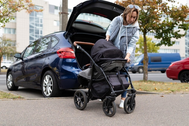 Foto il genitore della giovane donna ripiega il passeggino nel bagagliaio dell'auto