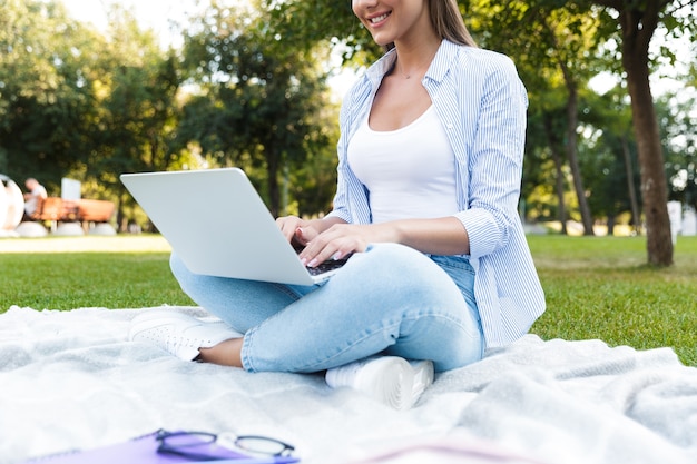 ラップトップコンピューターを使用して屋外の公園で若い女性。