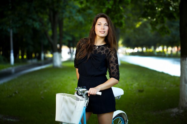 young woman in a park posing with a retro bicycle