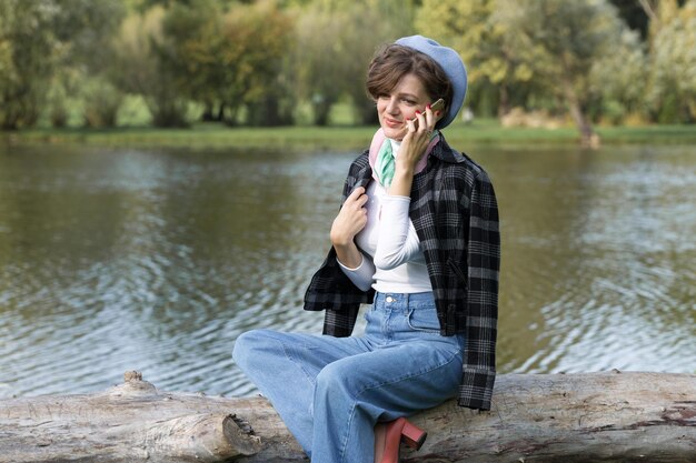 公園の若い女性が携帯電話で話すフランス風のかわいい女の子の肖像画