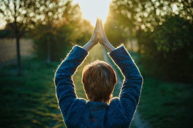 Young woman in park welcomes sunshine