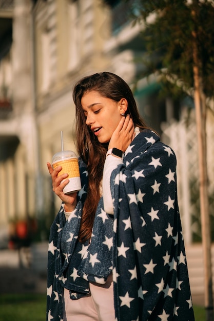 Young woman in the park with a paper glass of coffee