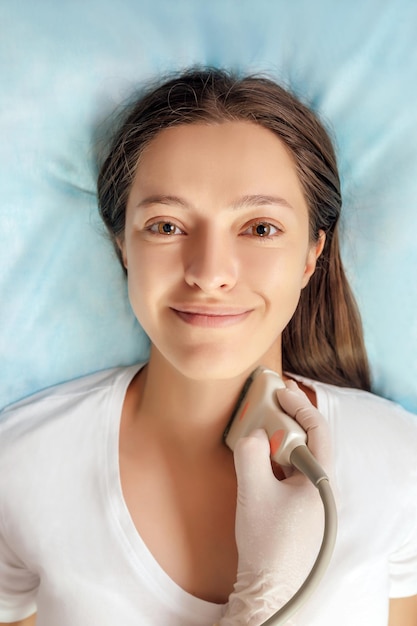 Young woman patient during the ultrasound examination of a thyroid lying on the couch in medical office