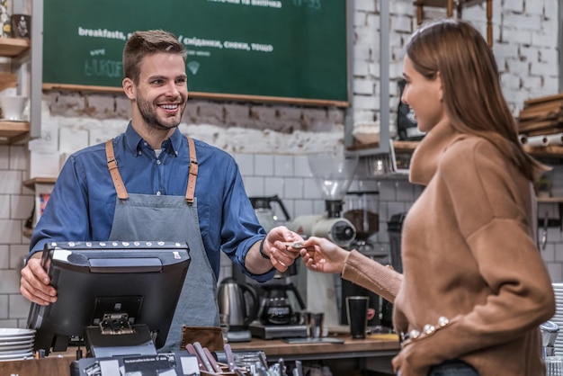 Photo young woman paying by credit card at cafe