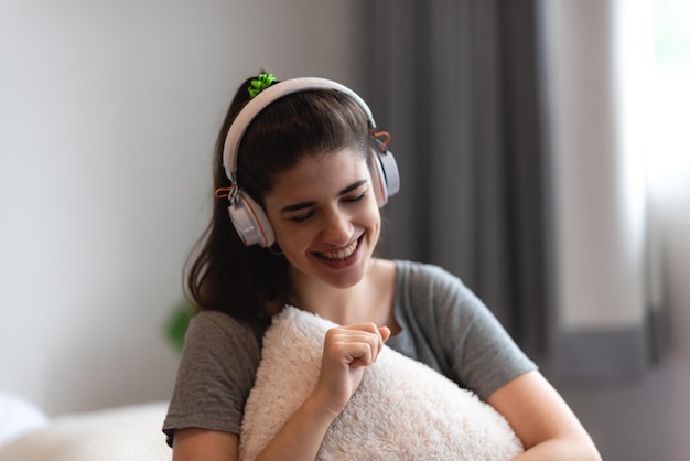 Young woman person wearing earphone or headphone to relaxing\
with song on the bed in bedroom at home concept of happy sound\
listen lifestyle in cozy audio feeling