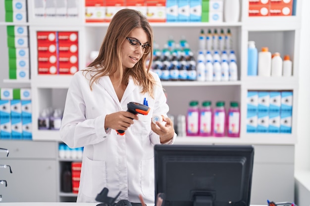 Foto bottiglia di pillole di scansione del farmacista della giovane donna alla farmacia