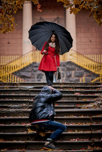 Giovane donna e fotografo nel parco sotto la pioggia.