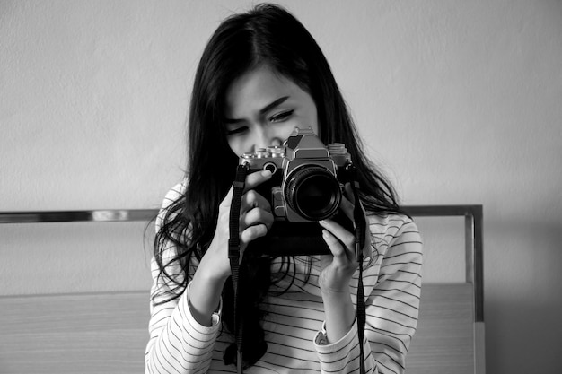 Young woman photographing against wall