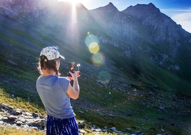 Foto giovane donna che fotografa il dente di leone in montagna