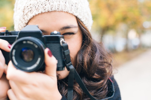 Молодая женщина фотографирует с помощью камеры в городе зимой