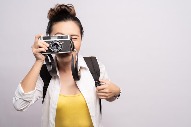 Photo young woman photographing while standing against gray background