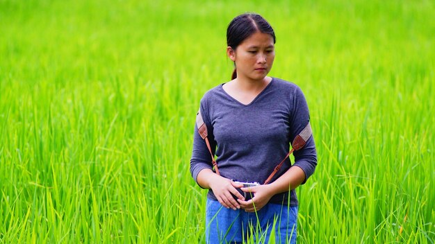 Young woman photographing with camera while standing at rice paddy