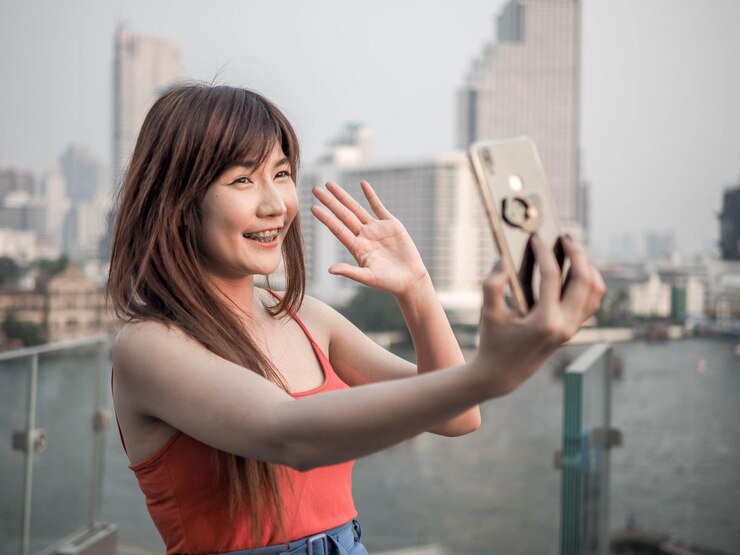 Photo 市内で携帯電話で写真を撮っている若い女性