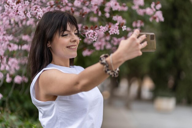 Young woman photographing with mobile phone while standing on plant