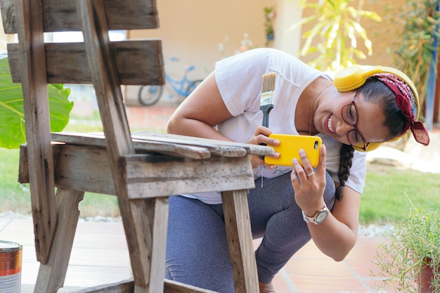 A young woman photographs a chair she is preparing to paint