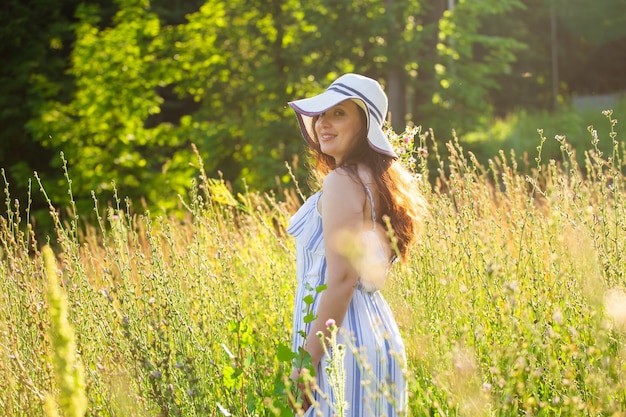 夏の夜に牧草地で花を摘む若い女性