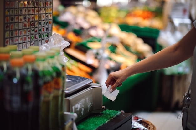 Young woman picks up receipt issued by self-service scales in
vegetable department. organization of trade . modern technologies.
convenience and self-service. everyday life.