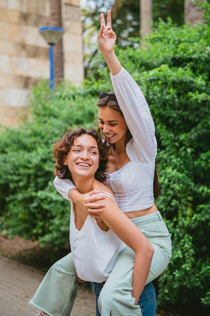 Young woman on a piggy back ride with her friend at a park in the city