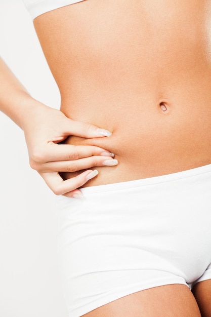 Young woman pinching waist and checking her body fat.