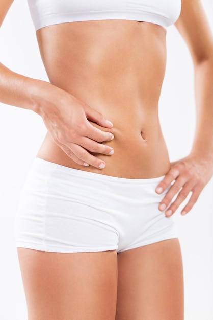 Young woman pinching waist and checking her body fat.