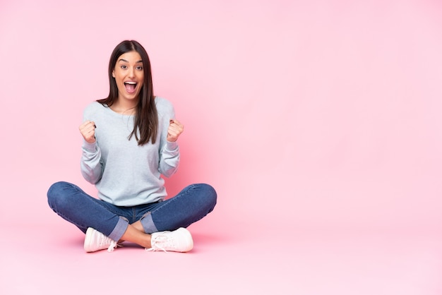 Giovane donna sul rosa che celebra una vittoria nella posizione del vincitore