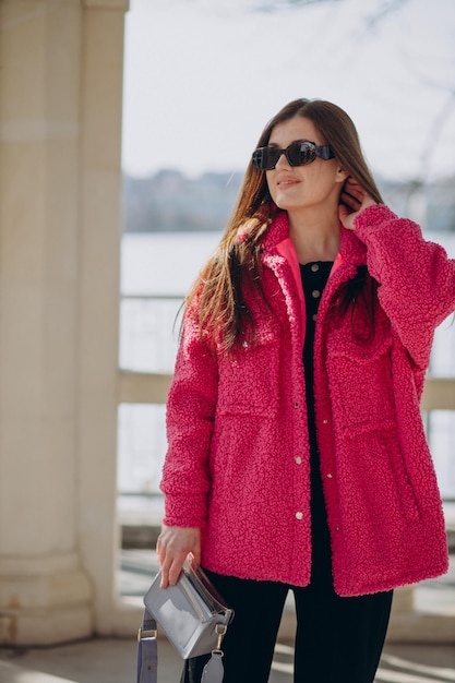 Young woman in pink coat standing in the street