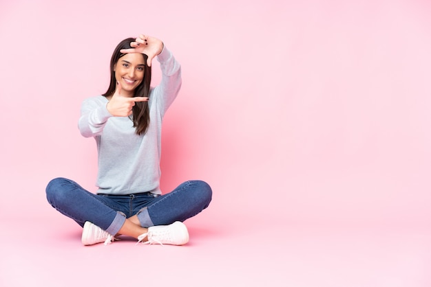 Young woman on pink focusing face. Framing symbol