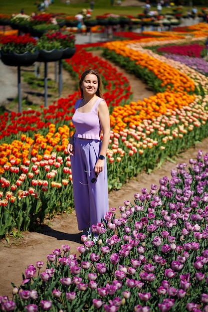 A young woman in a pink suit stands in a blooming field of tulips Spring time