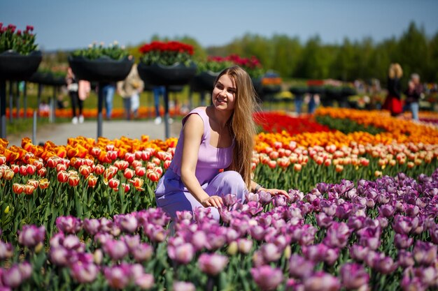 A young woman in a pink suit stands in a blooming field of tulips Spring time