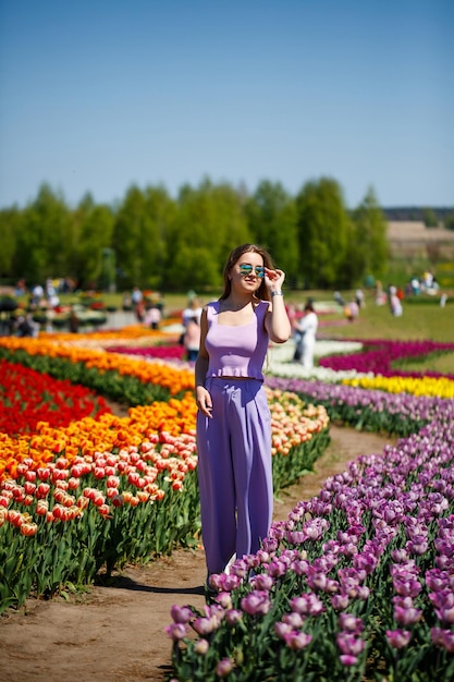 A young woman in a pink suit stands in a blooming field of tulips Spring time