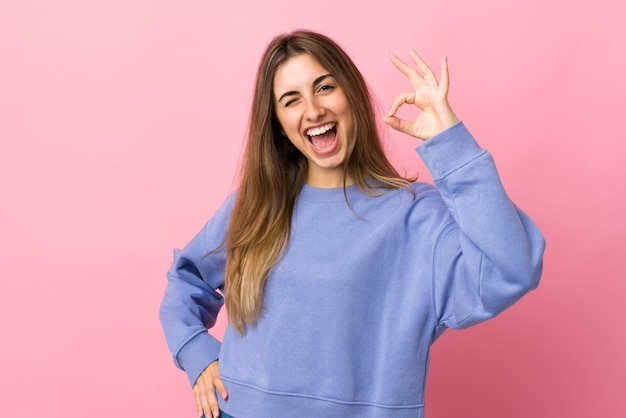 Young woman over pink wall showing ok sign with fingers