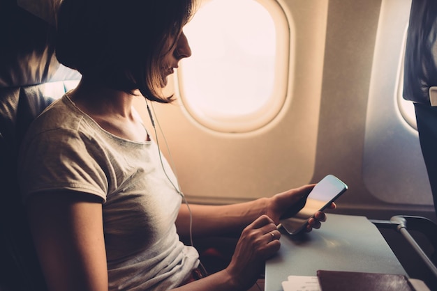 Young woman on a plane with a smartphone in her hands