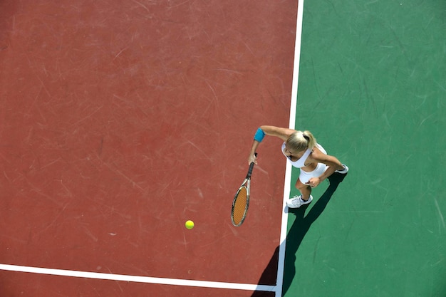 Молодая женщина играет в теннис на открытом воздухе