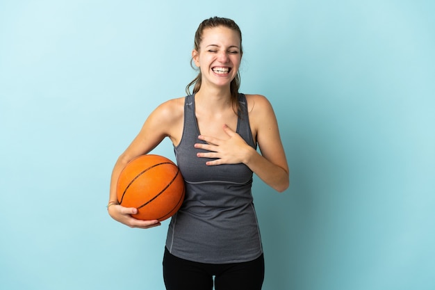 Молодая женщина играет в баскетбол на синем, много улыбаясь